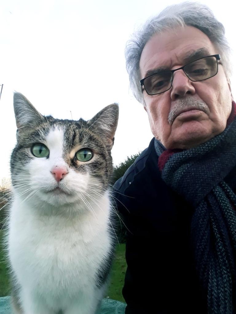 Ewald Roesenberger mit der Gartenkatze Paulinchen; die getigerte Katze mit weißem Fell sitzt im Vordergrund.